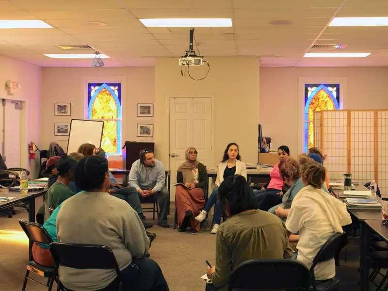 Group of people sitting in a circle on folding chairs